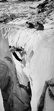 Ome Daiber (L) and Wolf Bauer (R) raise Dee Molenaar and victim during crevasse rescue practice on the Nisqually Glacier, 1950s.